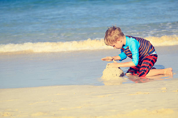 istock little boy play with sand on summer beach 540984560