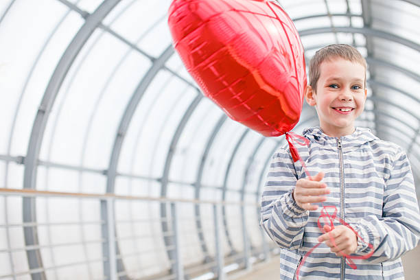 istock joyful boy with red balloon heart in hands 540984954
