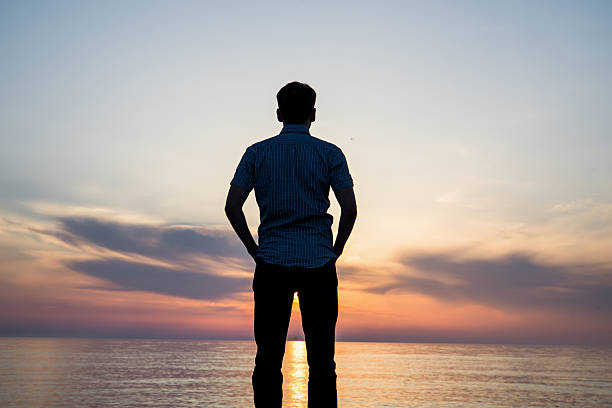 istock Silhouette of young man on the beach at sunset 540986624