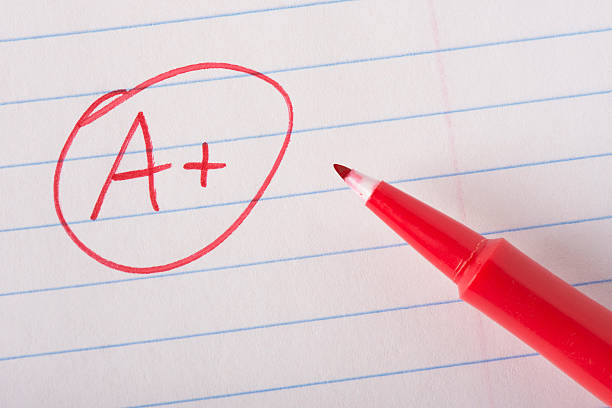 Perfect grade with pen A plus (A+) grade written in red pen on notebook paper with the pen sitting there. report card stock pictures, royalty-free photos & images