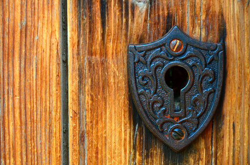 A close up image of a vintage lock on an old wooden door.