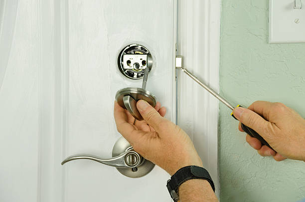 Repairing installing door deadbolt lock on house closeup Closeup of a professional locksmith is installing or repairing a new deadbolt lock on a house exterior door with the inside internal parts of the lock visible. door repairman men manual worker stock pictures, royalty-free photos & images