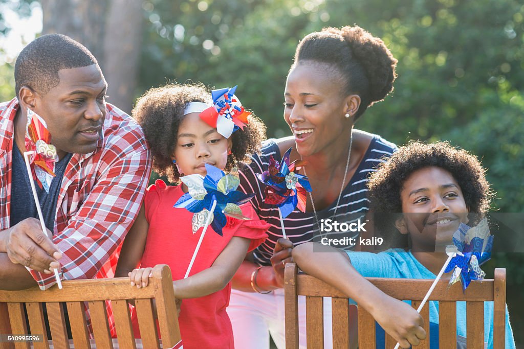 Family celebrating Memorial Day or July 4th A mixed race African American family of four outdoors celebrating an American patriotic holiday, perhaps Memorial Day or July 4th. They are playing with red, white and blue pinwheels. The children are part black, Asian and Hispanic. US Memorial Day Stock Photo