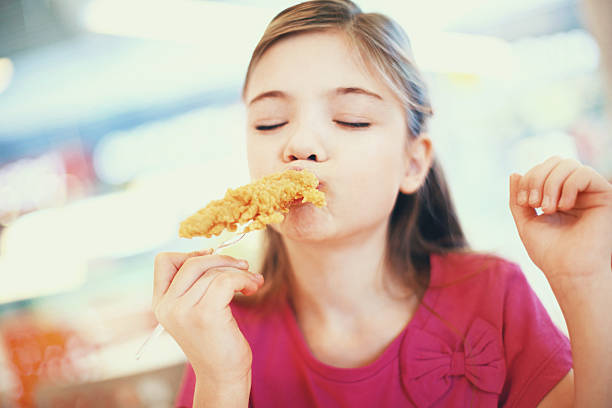 Little girl eating fried chicken.