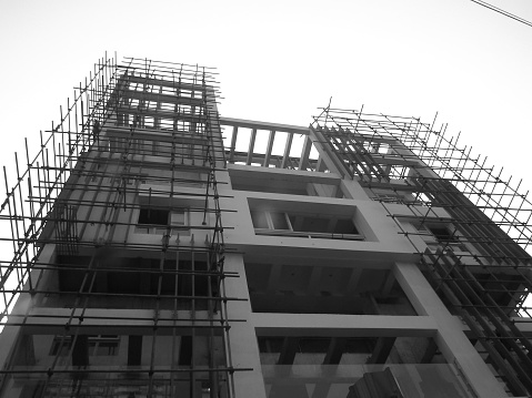 A high rise building under construction with the main building almost complete and surrounded by a bamboo framework