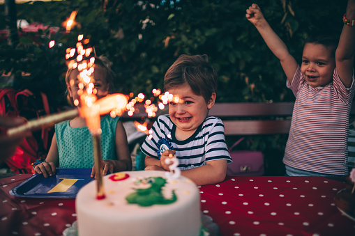 Photo of a children at a birthday party blowing out candles on a birthday cake 