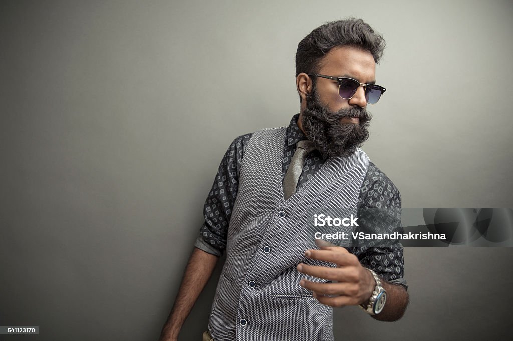 Young man posing with beard Young man posing with beard in suit with eye wear on grey background Men Stock Photo