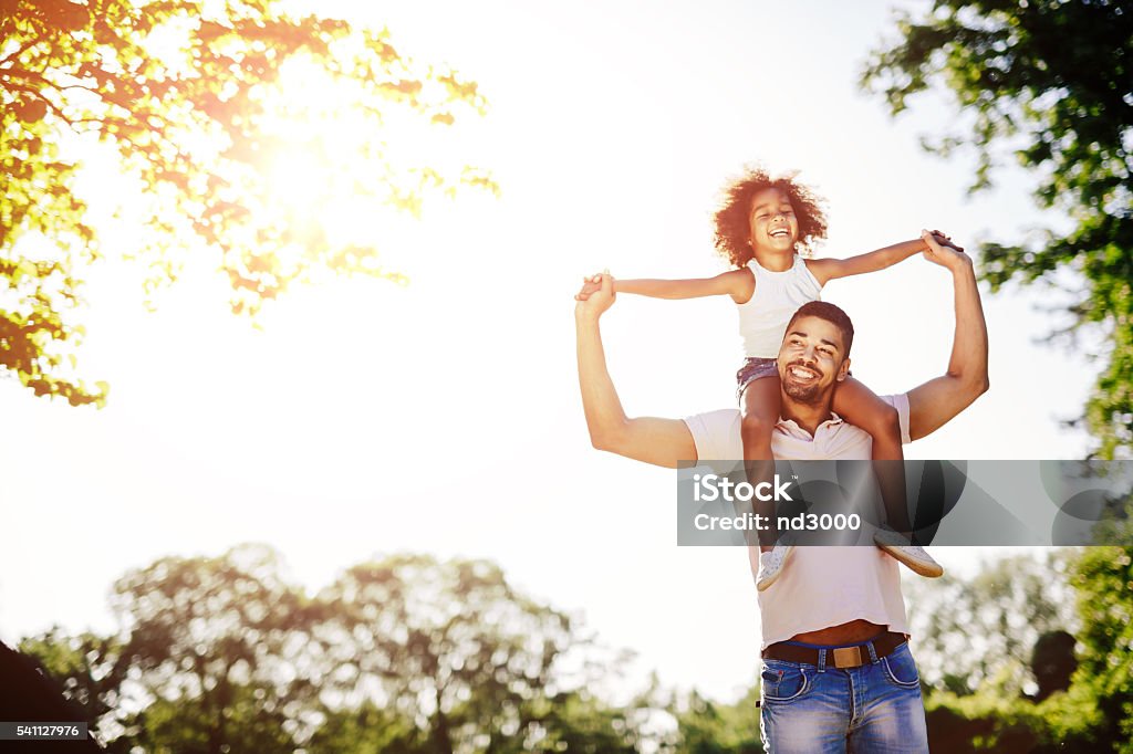 Father carrying daughter piggyback Father carrying daughter piggyback and being truly happy Carrying On Shoulders Stock Photo