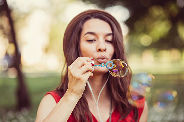 istock Young woman blowing soap bubbles 541139018
