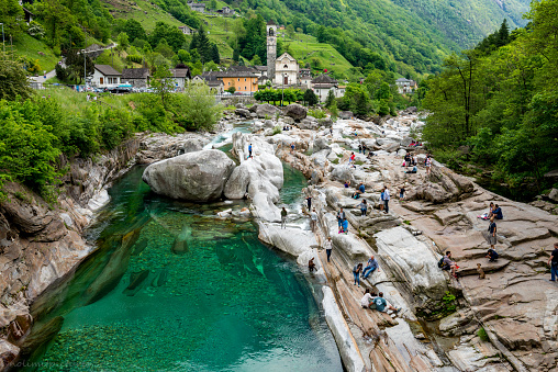 Lavertezzo, Italy - May 22, 2016: Beautiful nature and church in valley verzasca in Switzerland. Church belong zu little town Lavertezzo. Many people having fun walking on the stones in the water.