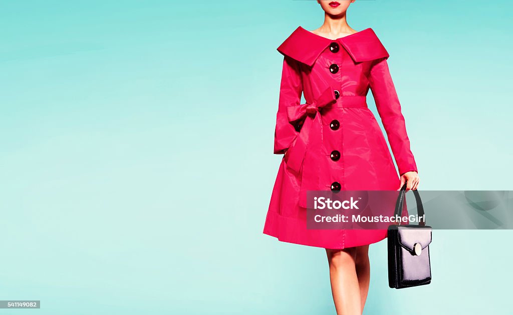 Red coat woman with black leather handbag. Beautiful vintage style. Fall winter fashion image. isolated on blur green background. Vintage retro style. Haute Couture Stock Photo