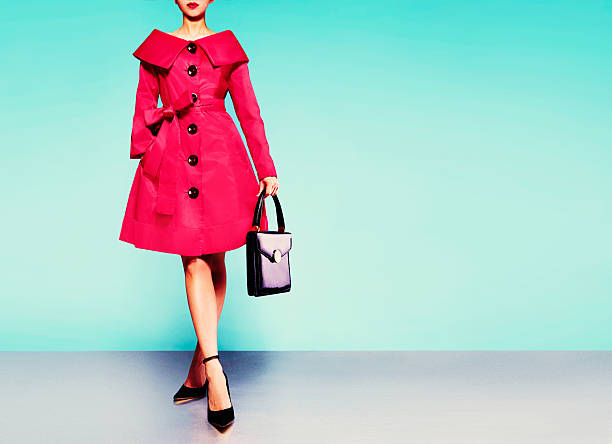 Red coat woman with black leather handbag with heels shoes. Fall winter fashion image. isolated on blur green background. Vintage retro style. fashion show stock pictures, royalty-free photos & images