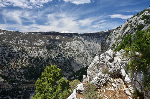 A distance view of a female rock climber enjoying the challenge of climbing the steep mountain cliffs