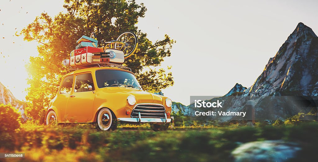 Cute little retro car goes by countryside road at sunset Cute little retro car with suitcases and bicycle on top goes by wonderful countryside road at sunset Car Stock Photo