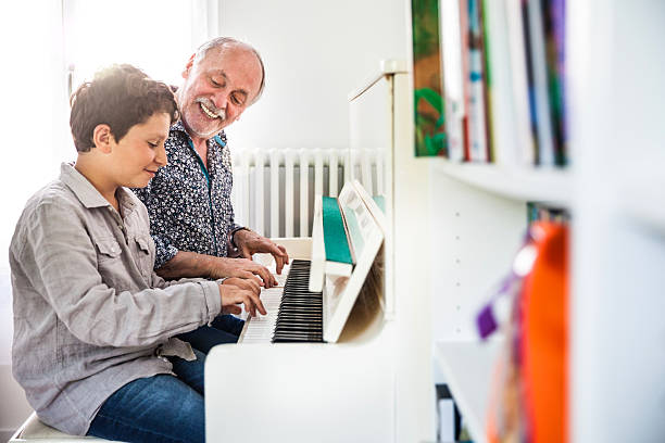 Little boy playing piano with his grandfather