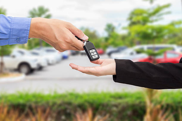 Businesswomen giving a key car to businessman at car parking stock photo