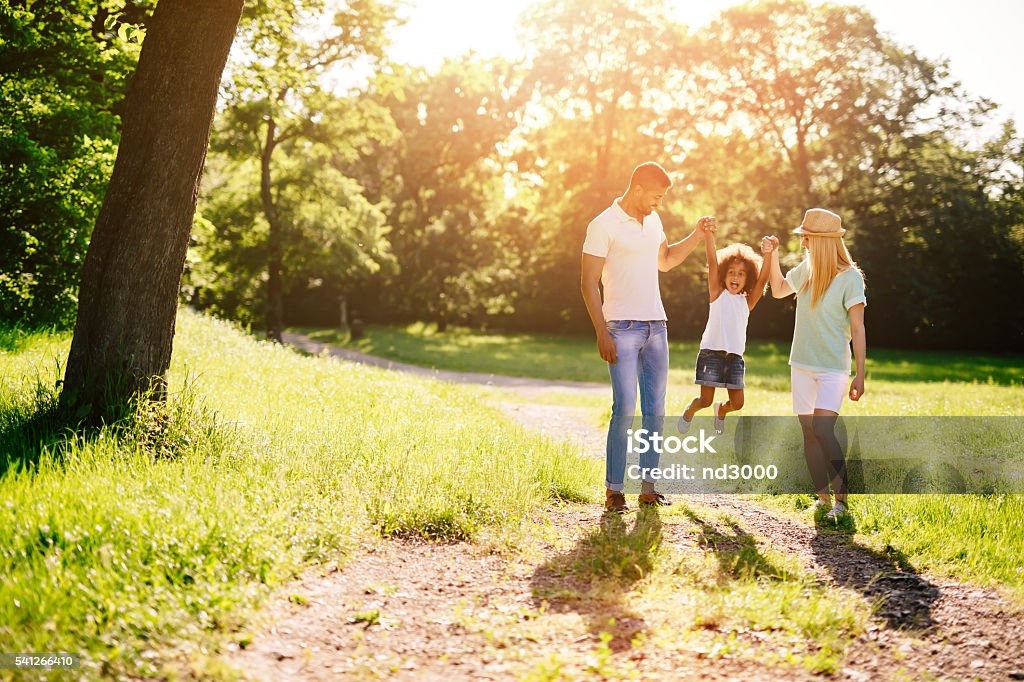 Mother and father swinging daughter Mother and father swinging daughter outdoors Family Stock Photo