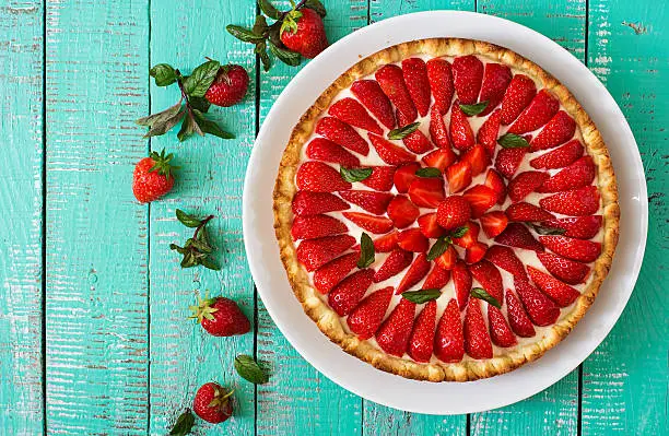 Tart with strawberries and whipped cream decorated with mint leaves. Top view