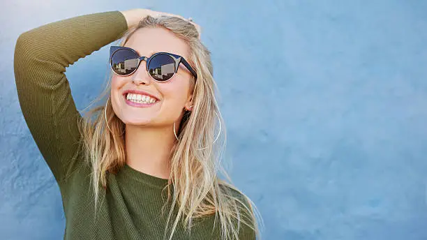 Photo of Stylish young woman in sunglasses smiling