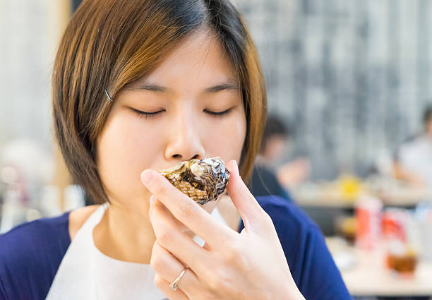 istock Cute Asian girl closed eye Deeply testing the Fresh Oysters 541277380