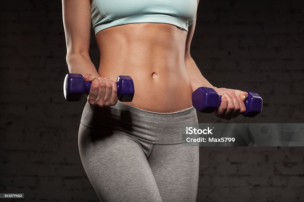 Fitness woman with muscular body, do her workout with dumbbells Fitness female woman with muscular body, do her workout with dumbbells, abs, abdominals Abdominal Muscle Stock Photo