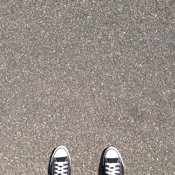 Black sneakers on asphalt, top view