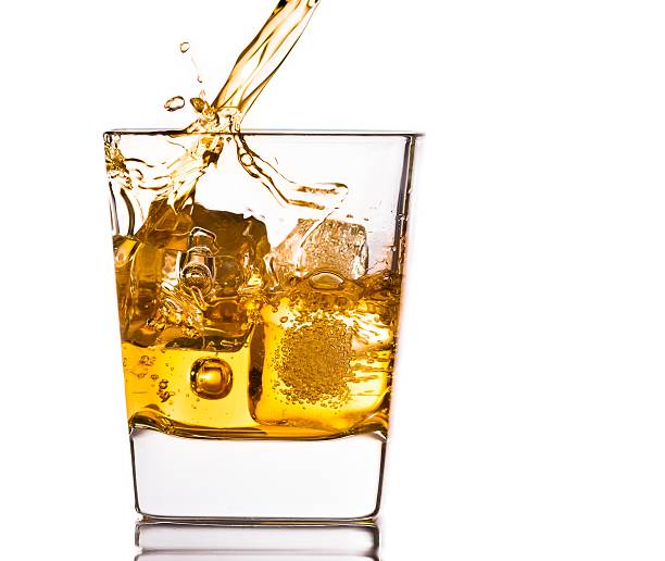 istock pouring scotch whiskey in glass with ice cubes on white 541279294