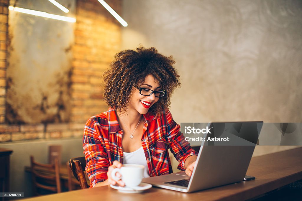 Coffee break Young woman siting at cafe drinking coffee and working on laptop Women Stock Photo