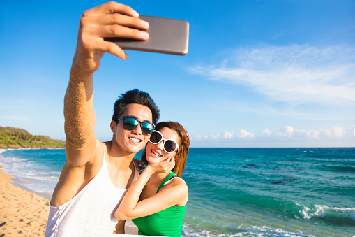 young couple  taking vacation selfie photograph at the beach..