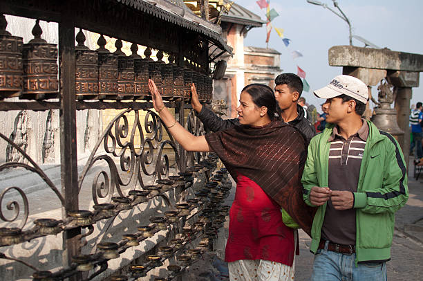 Prayer at Swayambhunath Stupa Kahtmandu, Nepal - November 10, 2012: Visitor at Swayambhunath Stupa circling the the holy temple surrounded by tibetan prayer wheels prayer wheel nepal kathmandu buddhism stock pictures, royalty-free photos & images