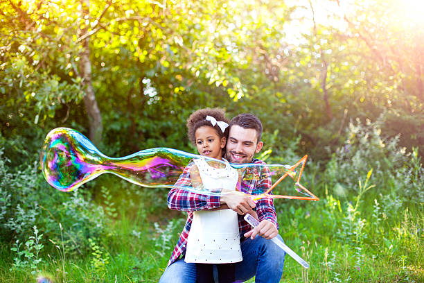 istock Happy father and daughter playing soap bubbles in park. 541292654