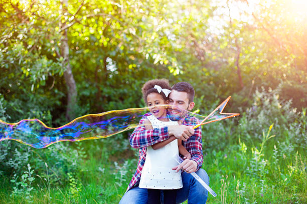 istock Happy father and daughter playing soap bubbles in park. 541292678