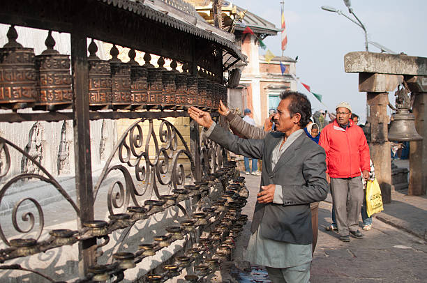 Prayer at Swayambhunath Stupa Kahtmandu, Nepal - November 10, 2012: Visitor at Swayambhunath Stupa circling the the holy temple surrounded by tibetan prayer wheels prayer wheel nepal kathmandu buddhism stock pictures, royalty-free photos & images