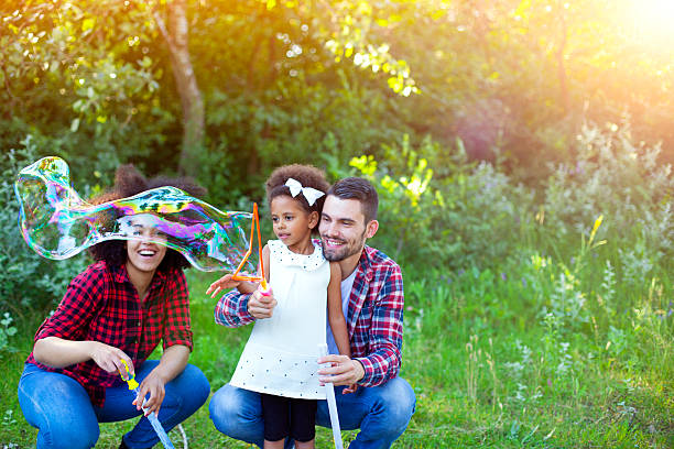 istock Happy family playing soap bubbles in park. 541292752