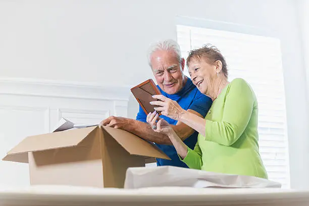 Photo of Senior couple packing box, looking at picture frame