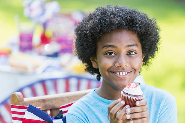istock Mixed race boy having cupcake at 4th of July picnic 541295022