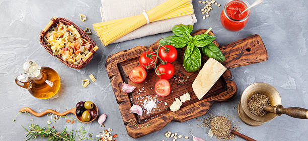 イタリア料理の背景 トマト、バジル、スパゲッティ、パルメザンチーズ、オリーブオイル、ニンニク - garlic cooking oil cutting board horizontal ストックフォトと画像