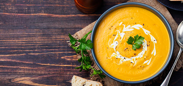 Pumpkin and carrot soup with cream and parsley Pumpkin and carrot soup with cream and parsley on dark wooden background Top view Copy space. pumpkin soup photos stock pictures, royalty-free photos & images