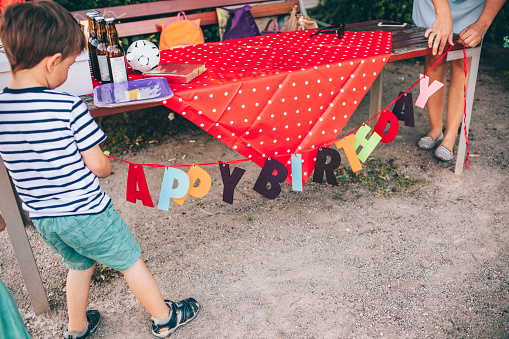 Photo of a little boy and his family, preparing a outdoors birthday party in a park 