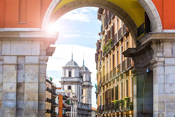 Gate in old town of Madrid, with church in the background.