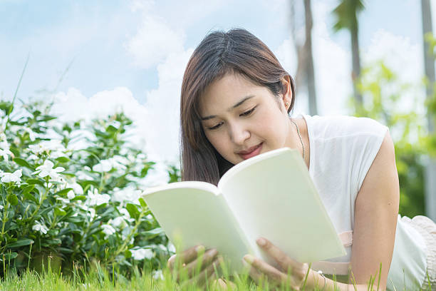 istock Asian woman lying on grass field for read a book 541568282
