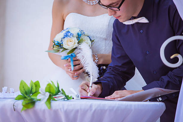 istock groom signing wedding certificate in park 541570112