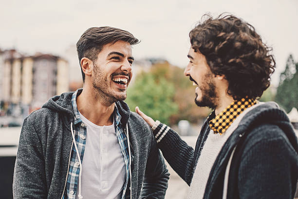 Two men talking and smiling on the street Two young men smiling and laughing at urban scene. street friends stock pictures, royalty-free photos & images