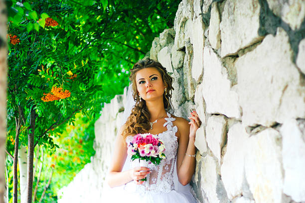 istock Beautiful young bride standing on a stone wall background 541573994