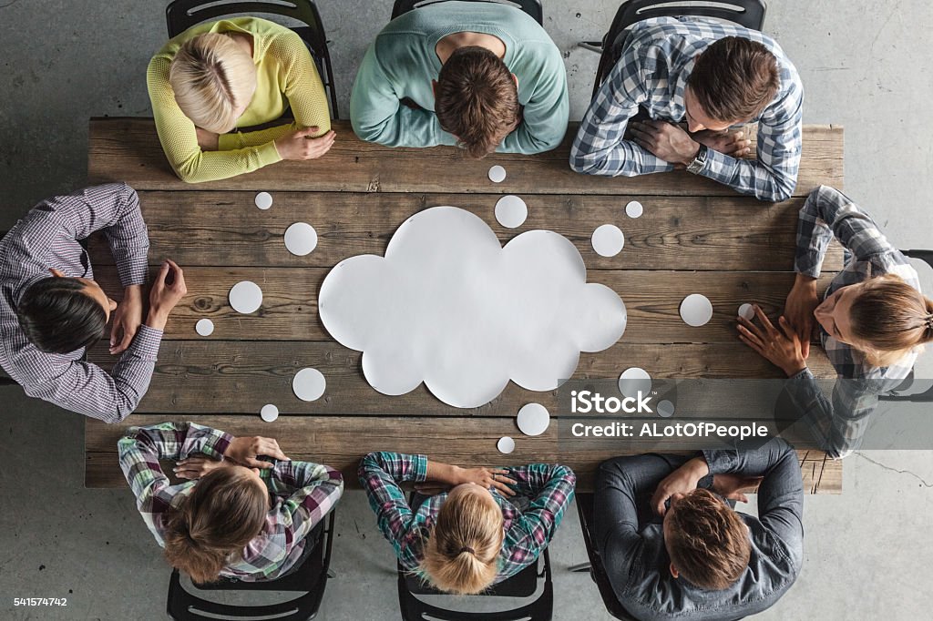 Teamwork meeting concept Hipster business teamwork brainstorming planning meeting concept, people sitting around the table with white paper shaped like dialog cloud Discussion Stock Photo