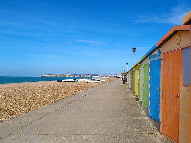 istock Colorful beach huts on pebble beach in England 541576898