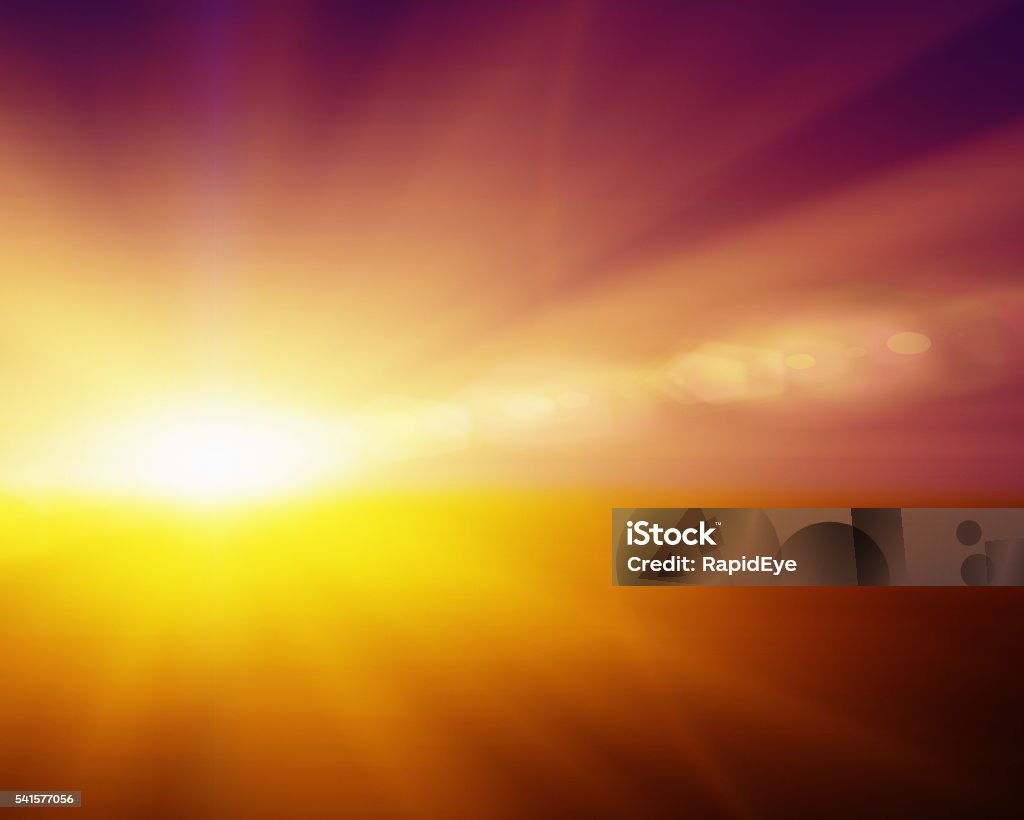 Dazzling sunrise or sunset; bright rays with copy space Dazzling sunrise or sunset with blazing sun on a background of gold deepening to orange, with radiating rays and lens flare. Ample copy space. Summer Solstice Stock Photo