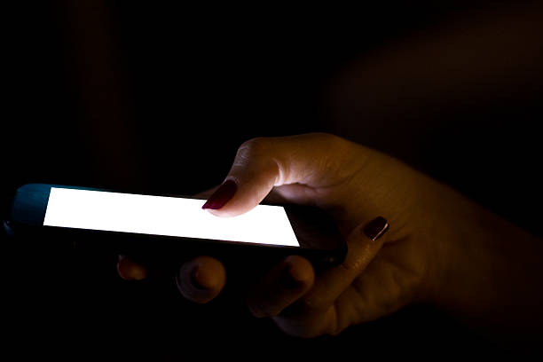 istock Woman's hand holding smart phone in dark 541581728