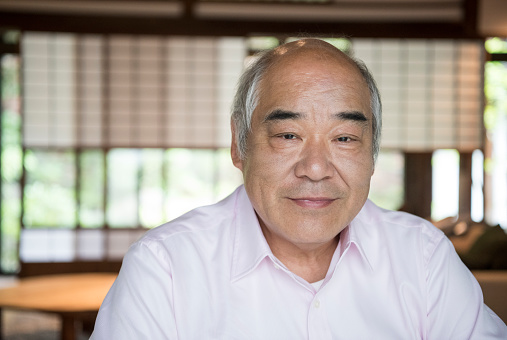 Senior man facing camera with contented expression. Head and shoulders of male Japanese senior