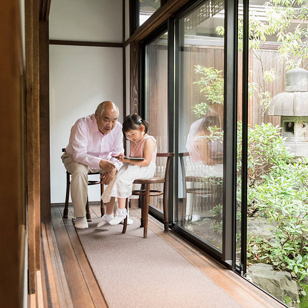istock Grandfather helping Japanese girl use digital tablet 541582146